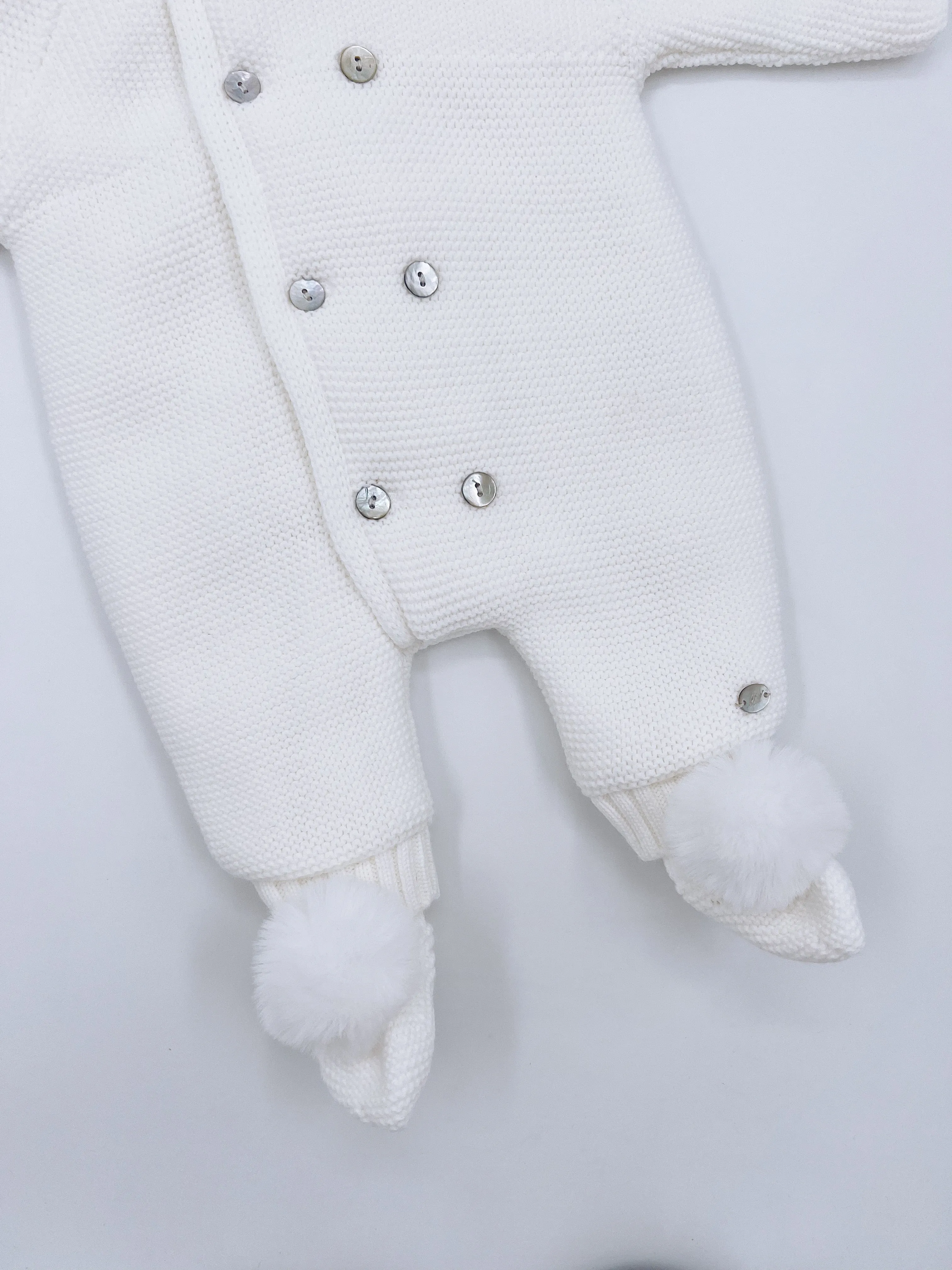 White knitted Baby pramsuit with matching knitted pompom booties.